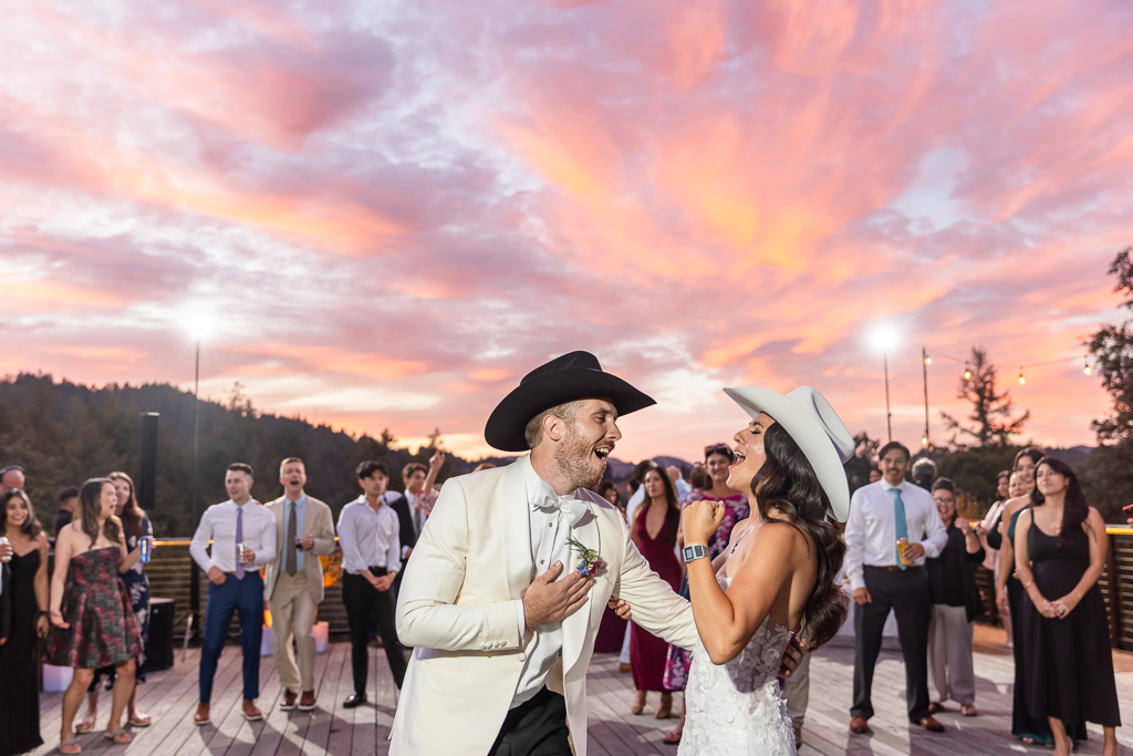 bride and groom as the center of attention on the dance floor under a glowing pink sky