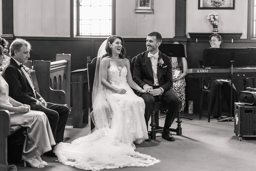 bride and groom holding hands and laughing during Catholic ceremony