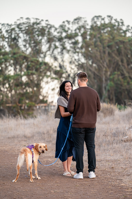 couple stopped to talk on a trail with their dog