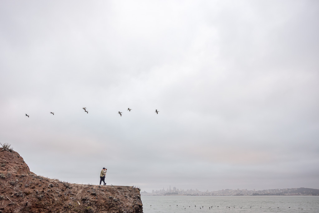 couple taking engagement photos set against the San Francisco skyline backdrop