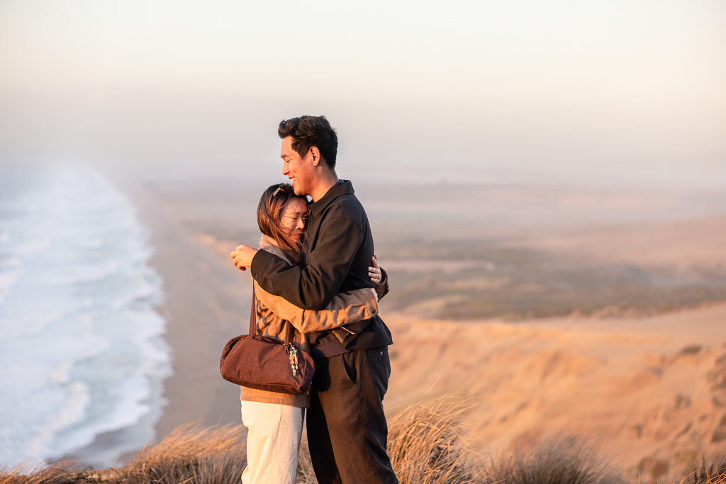 A tearful hug as the couple celebrates their engagement above the Pacific shoreline.