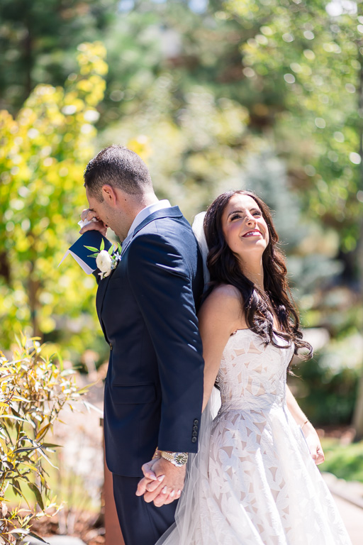Bride and groom hold hands in an emotional first touch in the Water Gardens