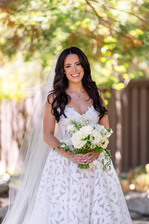 Bride holds her bouquet beneath the trees for a wedding portrait