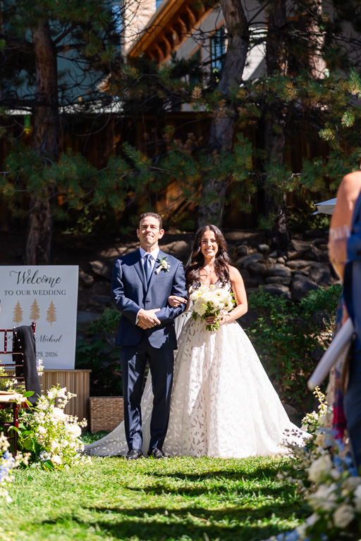 Bride and her father at the end of the aisle beside their welcome sign at Hyatt Regency Lake Tahoe Resort