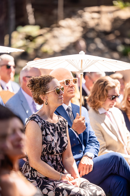 Guests at outdoor ceremony beneath white parasols