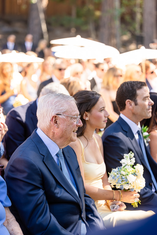 Wedding guests sit beneath parasols during the outdoor ceremony