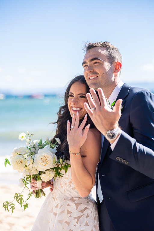 Bride and groom flashing their new wedding rings on the beach beside Lake Tahoe