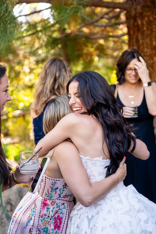 Bride shares a warm embrace with a guest during the outdoor celebration