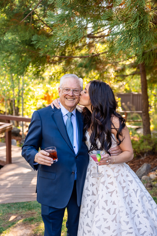 Bride kisses grandpa on the cheek at the outdoor reception