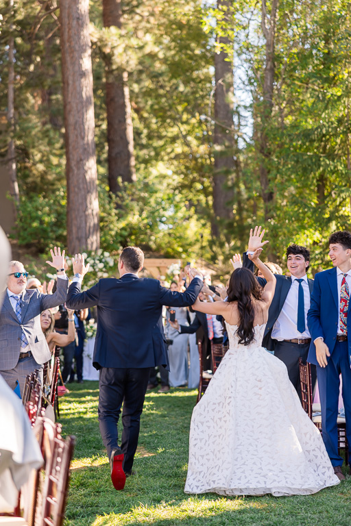 Bride and groom walk along the garden aisle for their grand entrance