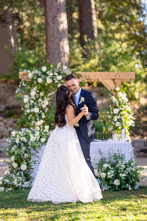 Bride and groom quietly dance beneath the floral arch