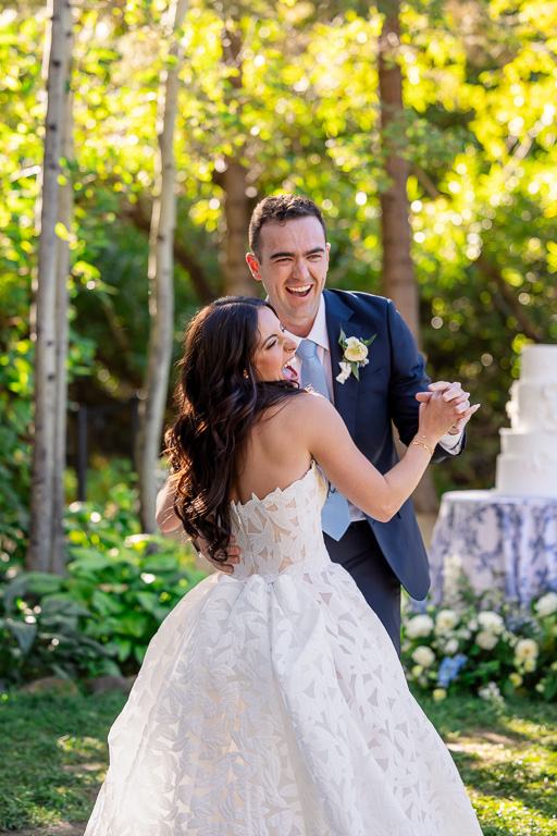 Bride and groom dance together beneath the trees