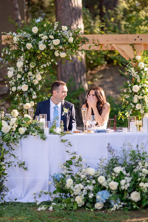 Bride and groom sit together at their reception table