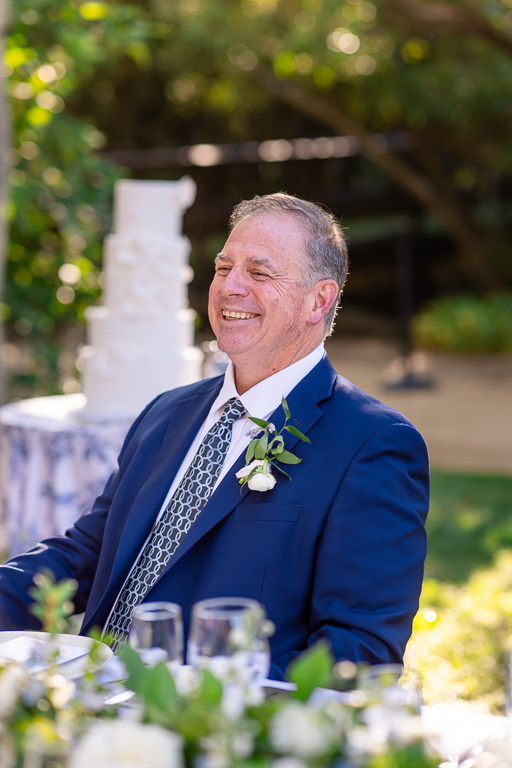 groom's father smiles during dinner speeches