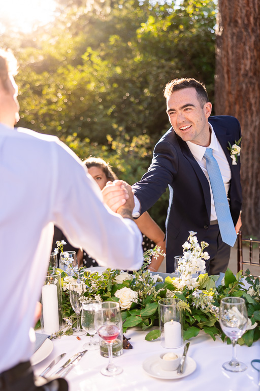 Groom greets a guest at the outdoor reception table