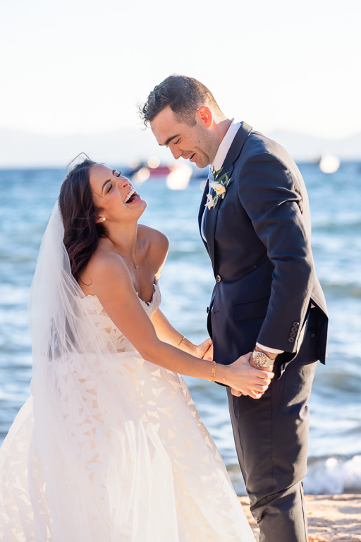 Bride and groom share a candid moment during wedding portraits beside Lake Tahoe
