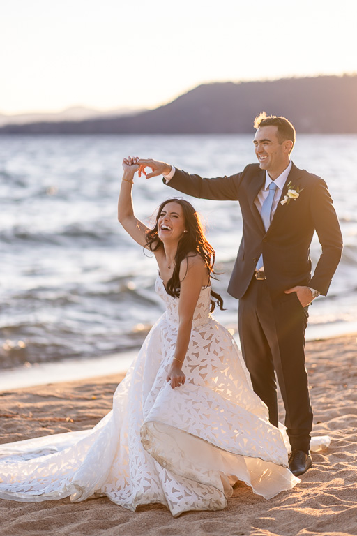 Groom twirls the bride on the Lake Tahoe beach at sunset