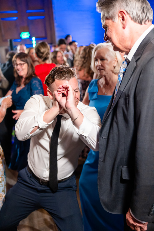 Wedding guest dances as another guest reacts with emotion