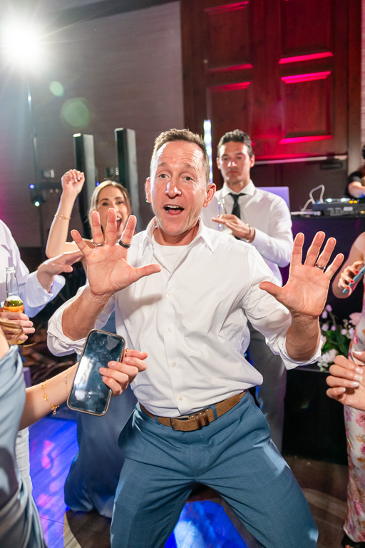 Wedding guest dances beneath colorful reception lights