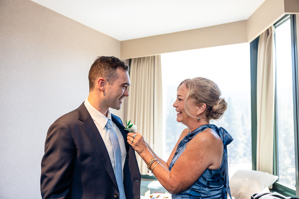 Groom’s mother pins his boutonniere before the wedding ceremony