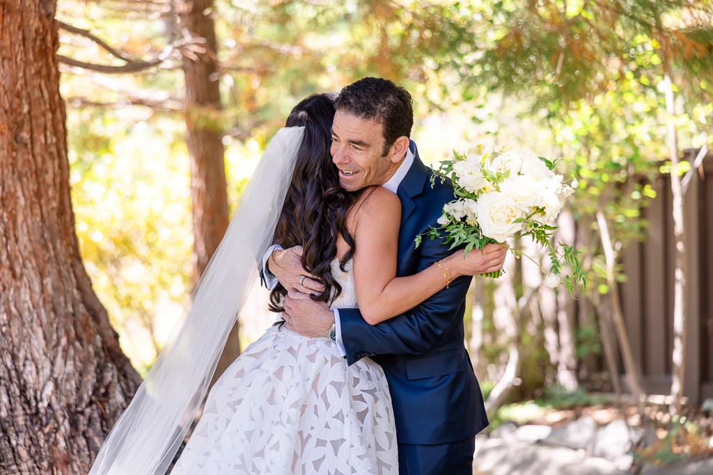 bride and dad embrace beneath a large tree during the dad first look
