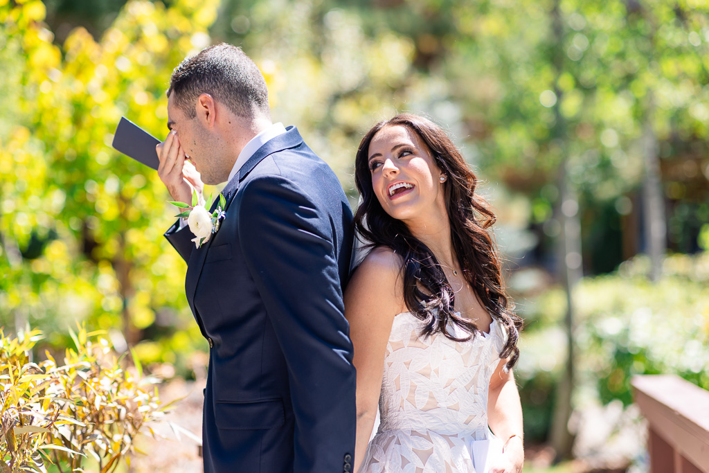 Groom wipes away tears as the bride smiles beside him