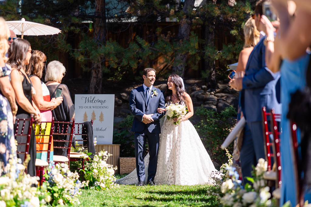 Wedding guests watch the bride’s entrance along the garden aisle