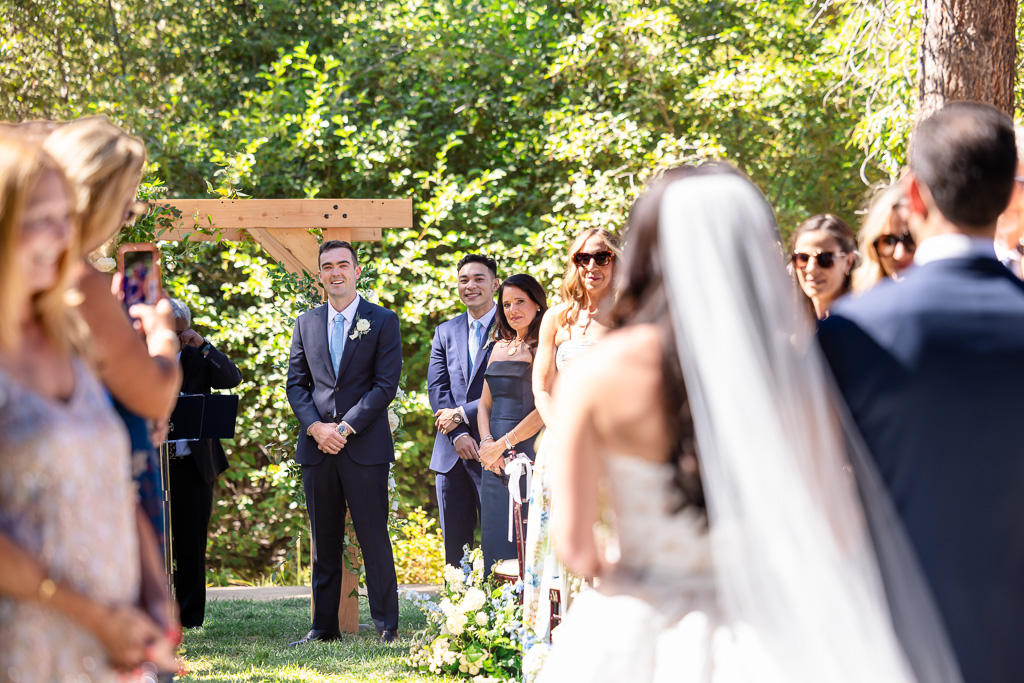 groom looking on as the bride and her dad walk up the aisle towards him in the hand-off