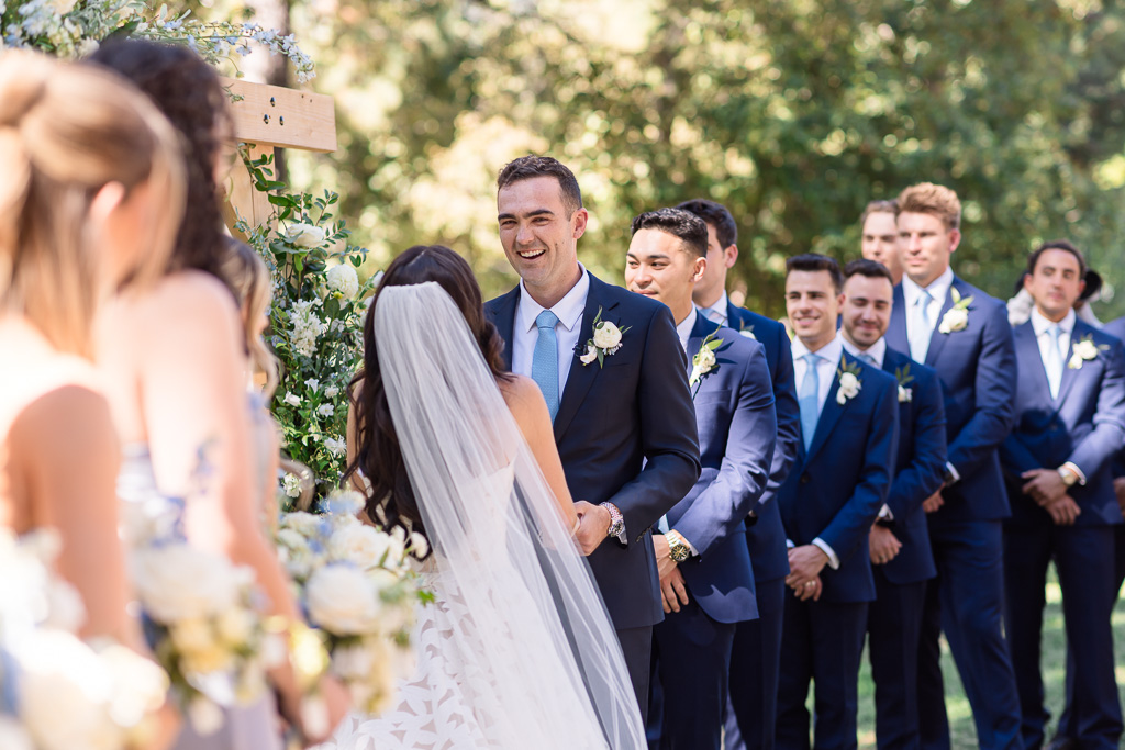 Bride and groom share a laugh as the groomsmen look on during their wedding ceremony