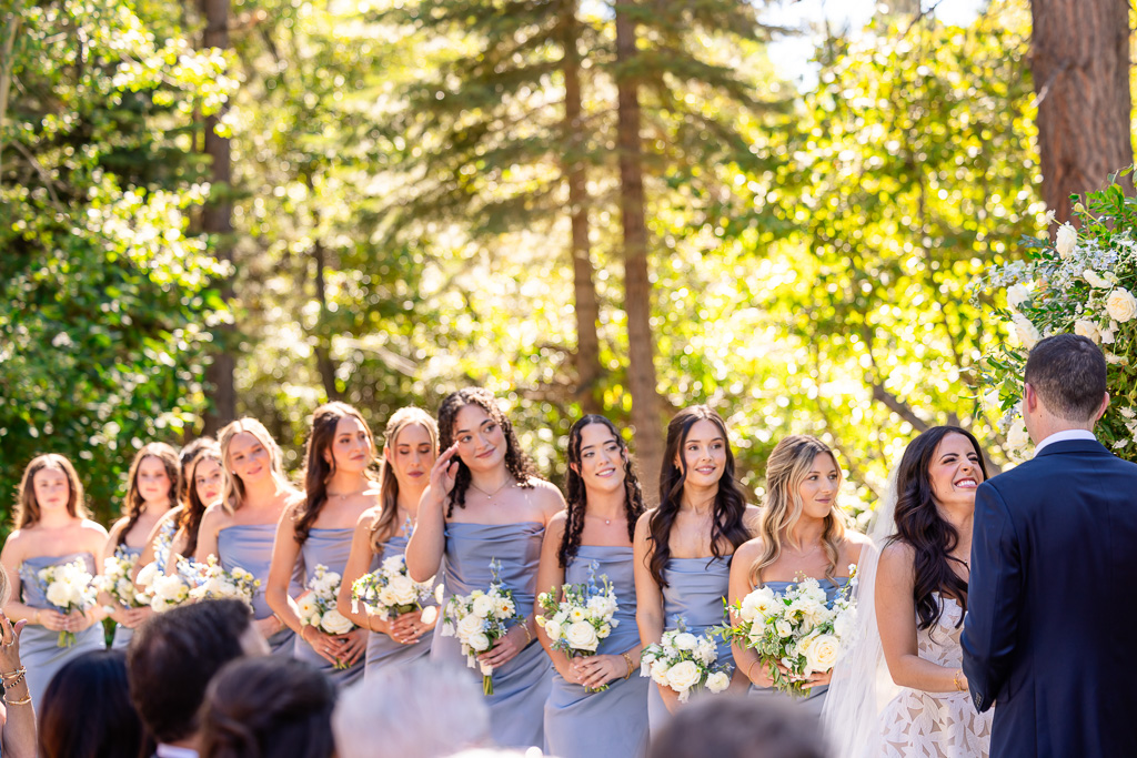 Bride makes a cute smile at the groom as her bridesmaids stand in line behind her