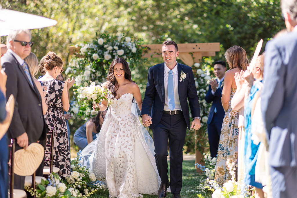 Bride and groom walking back down the aisle together with their wedding party behind them