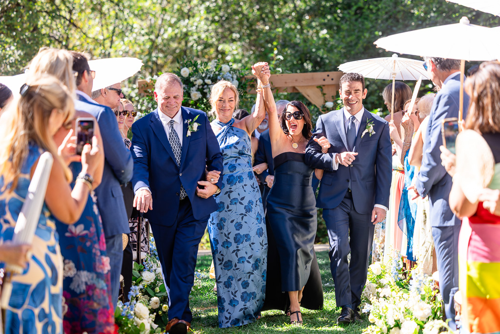 two sets of parents cheer and walk back down the aisle after their children got married
