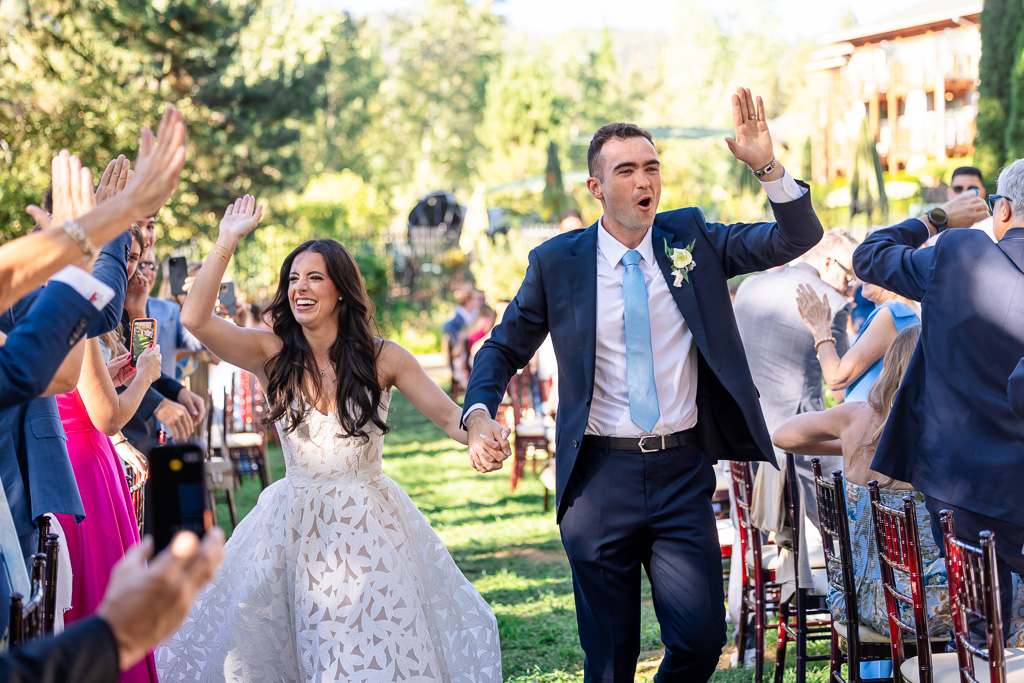 Bride and groom make their way through a cheering wedding crowd as they enter the reception