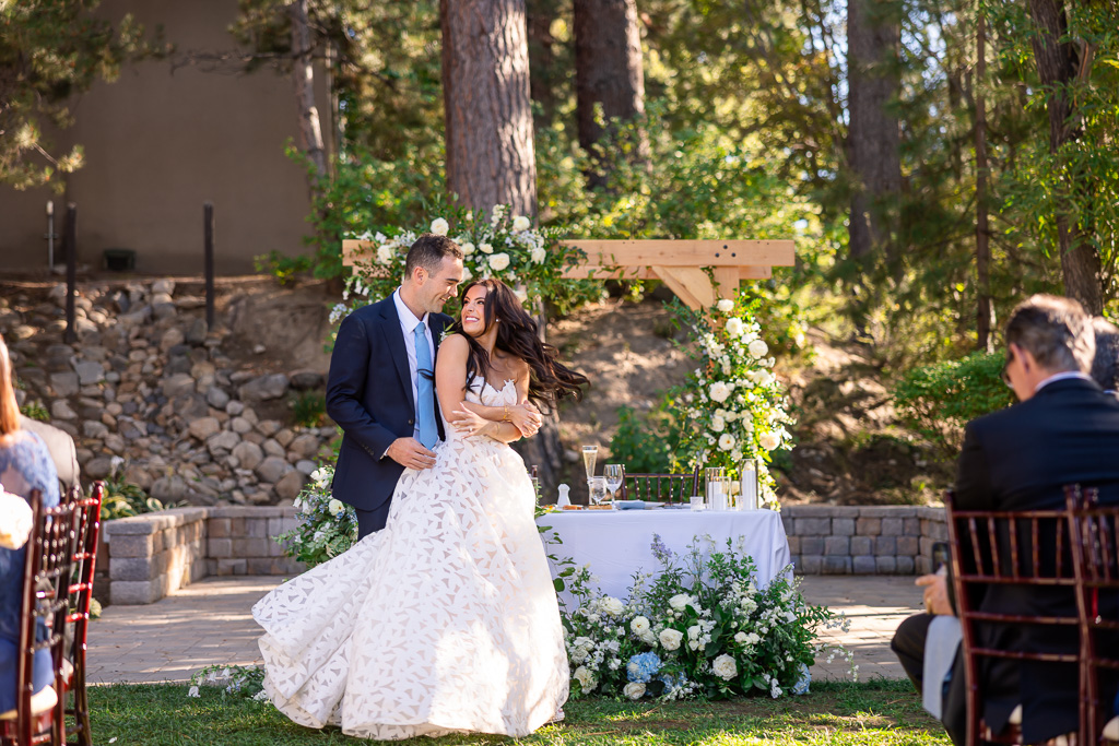 Bride and groom dance together beneath the floral ceremony arch