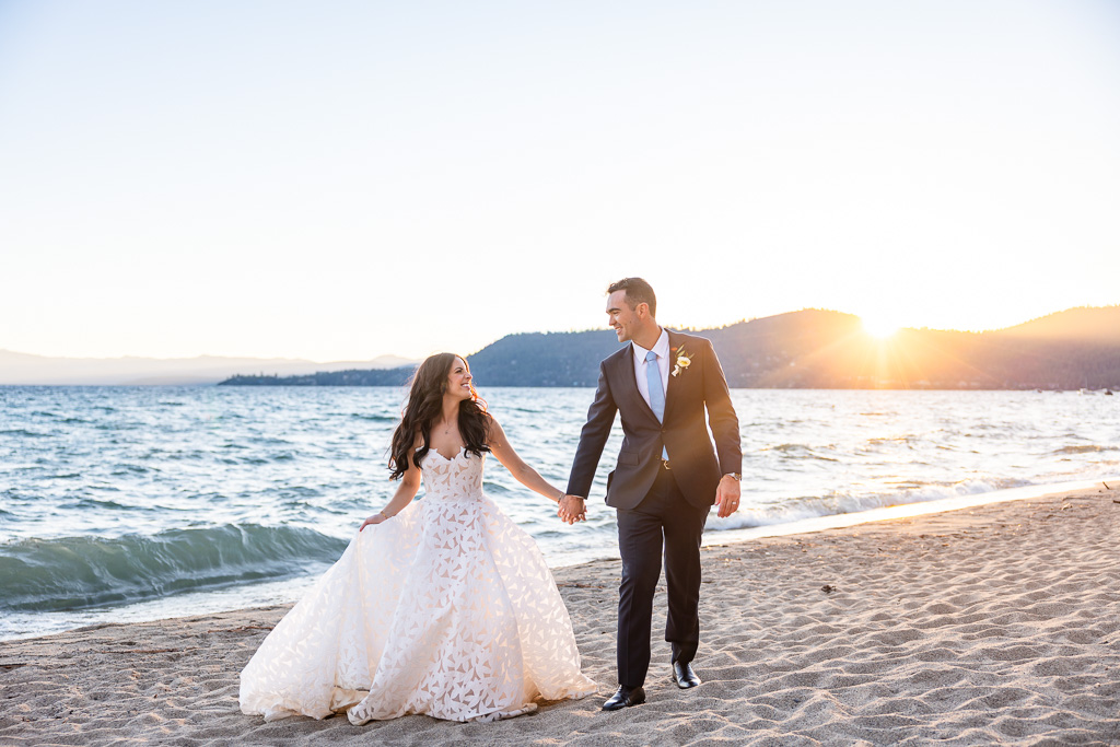 Newlyweds stroll together beside Lake Tahoe as the sun dips below the horizon