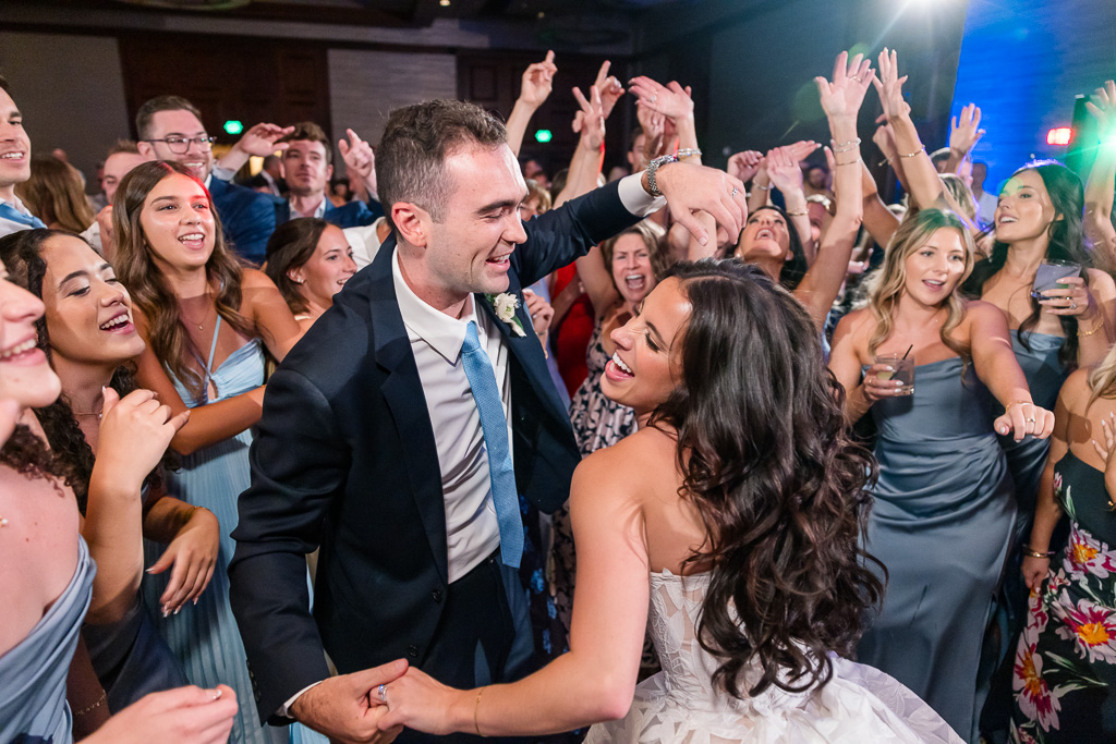 Bride and groom dance together amid the reception crowd to finish the night