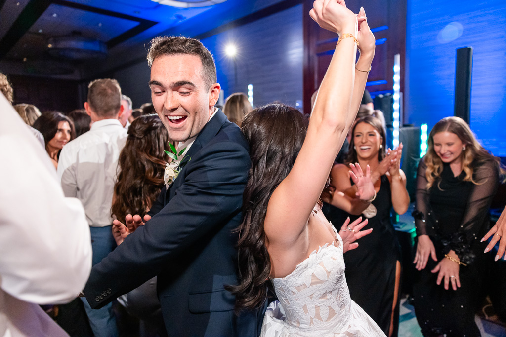 Bride and groom dance together as wedding guests celebrate