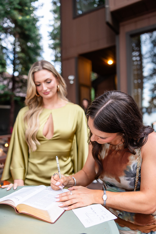 A guest signs a Bible guestbook and writes a note.