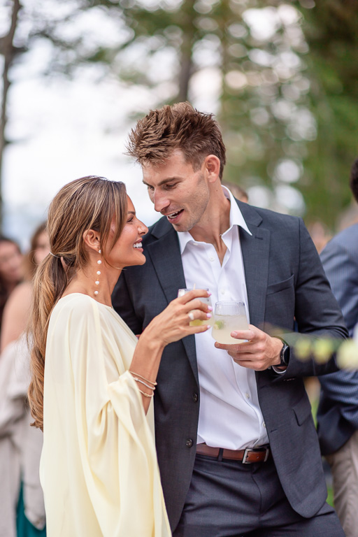 Two guests share a laugh and drinks at the outdoor celebration.