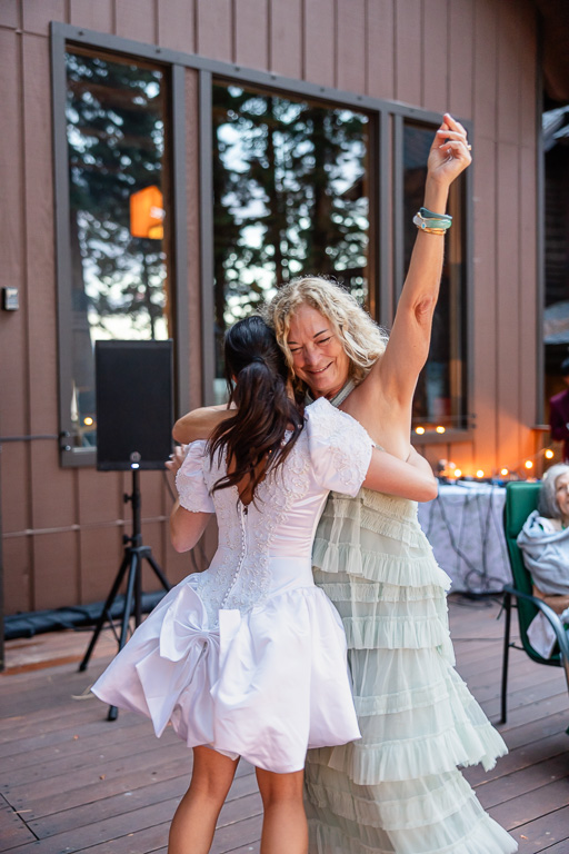 The bride dances with her mother-in-law on the wooden deck.