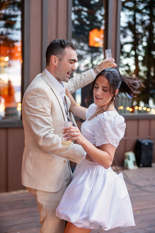 The bride and groom celebrate with drinks on the deck beneath the trees.