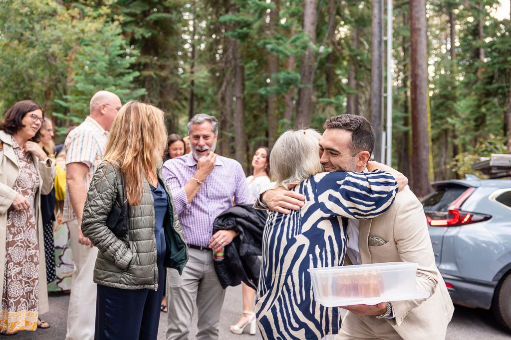The groom greets a guest with a warm hug near the driveway.