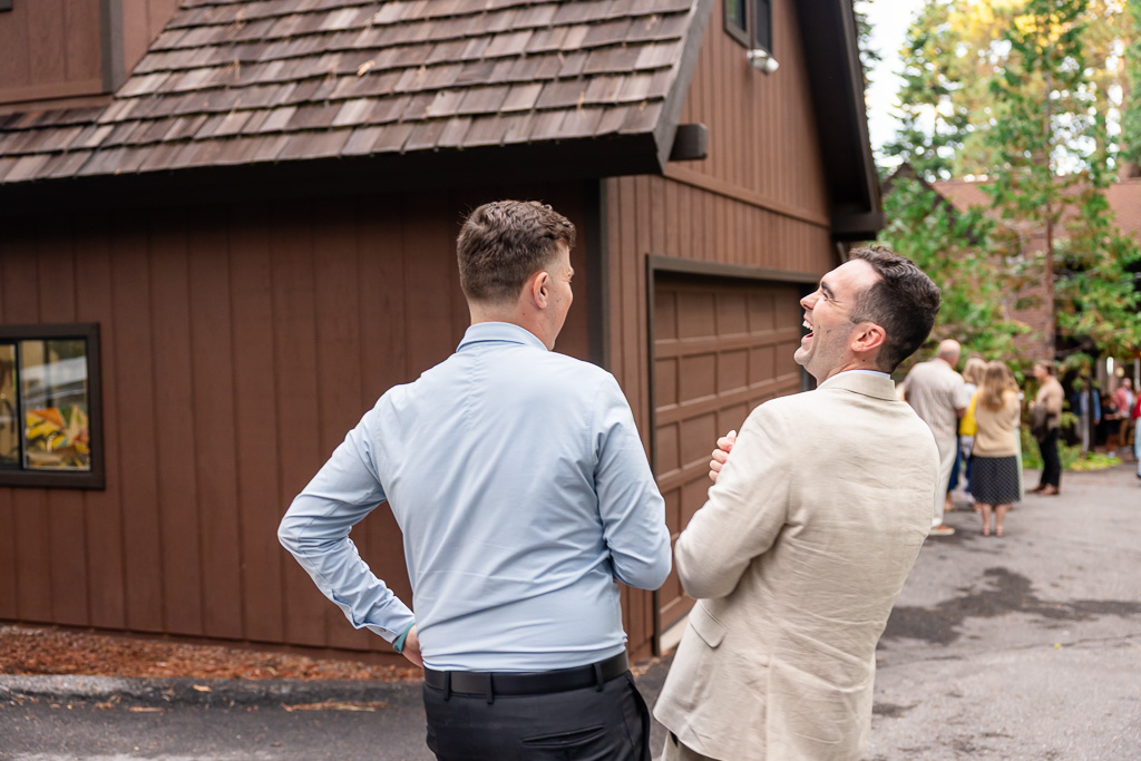 The groom laughs with a guest outside the family’s mountain home.
