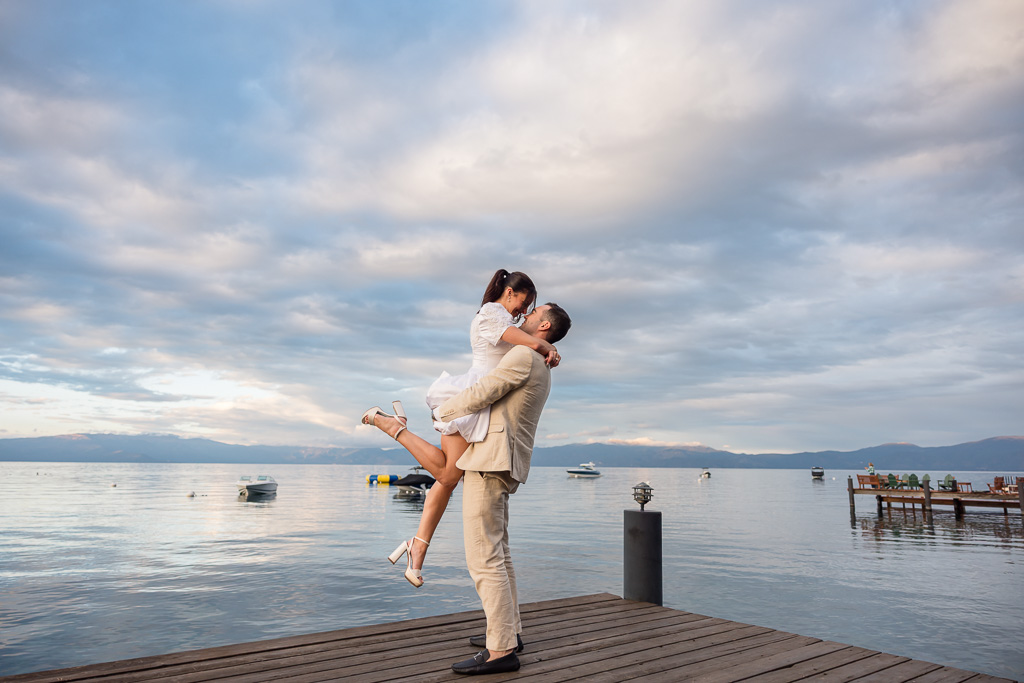 The couple shares a kiss as the groom lifts the bride on the dock at Lake Tahoe