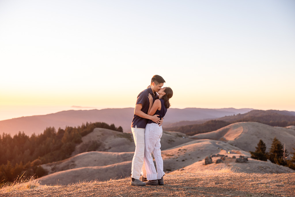 Couple kissing during a sunset engagement shoot atop rolling hills of Mt Tam