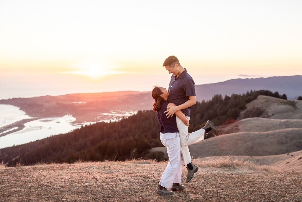Silly photo during engagement shoot of girl struggling to lift up her fiance