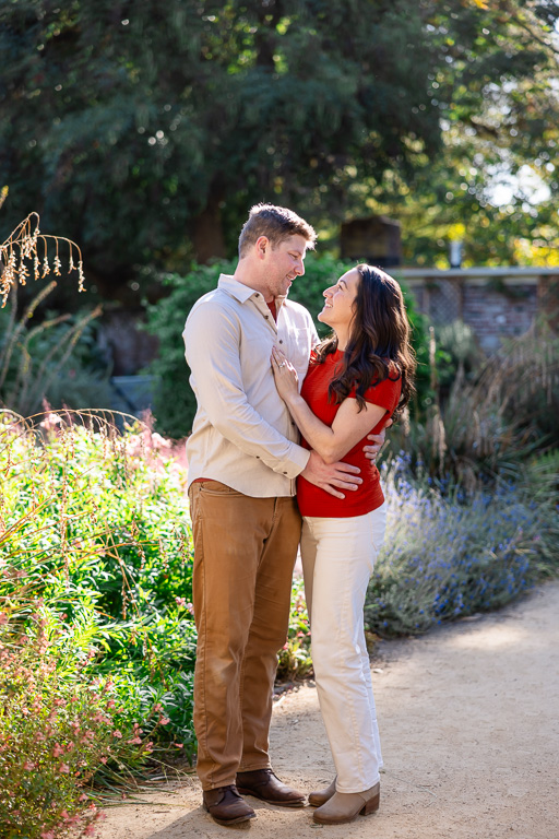 A couple shares a warm, close embrace among the sunlit flower beds at Elizabeth Gamble Garden.