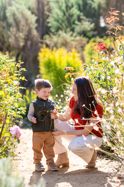 mom playing with her young son as they admire a small bundle of garden greenery together.