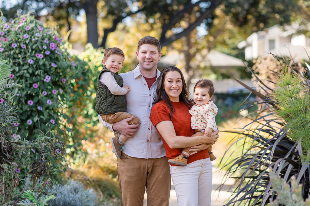 The family of four smiles together in an outdoor portrait at Elizabeth F Gamble Garden in Palo Alto.