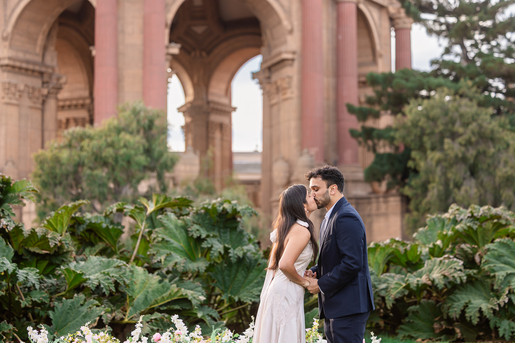 The newly engaged couple kisses beneath the grand arches of the Palace of Fine Arts